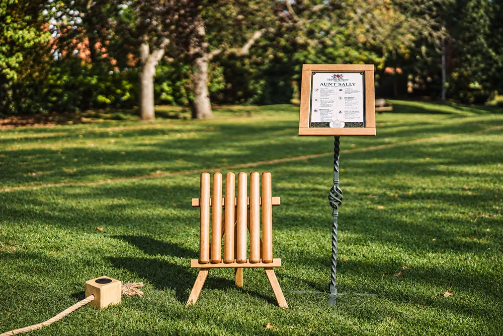 Close-up of a wooden deckchair with fabric back and a neatly draped blanket, by Thistle & Rose Events.
