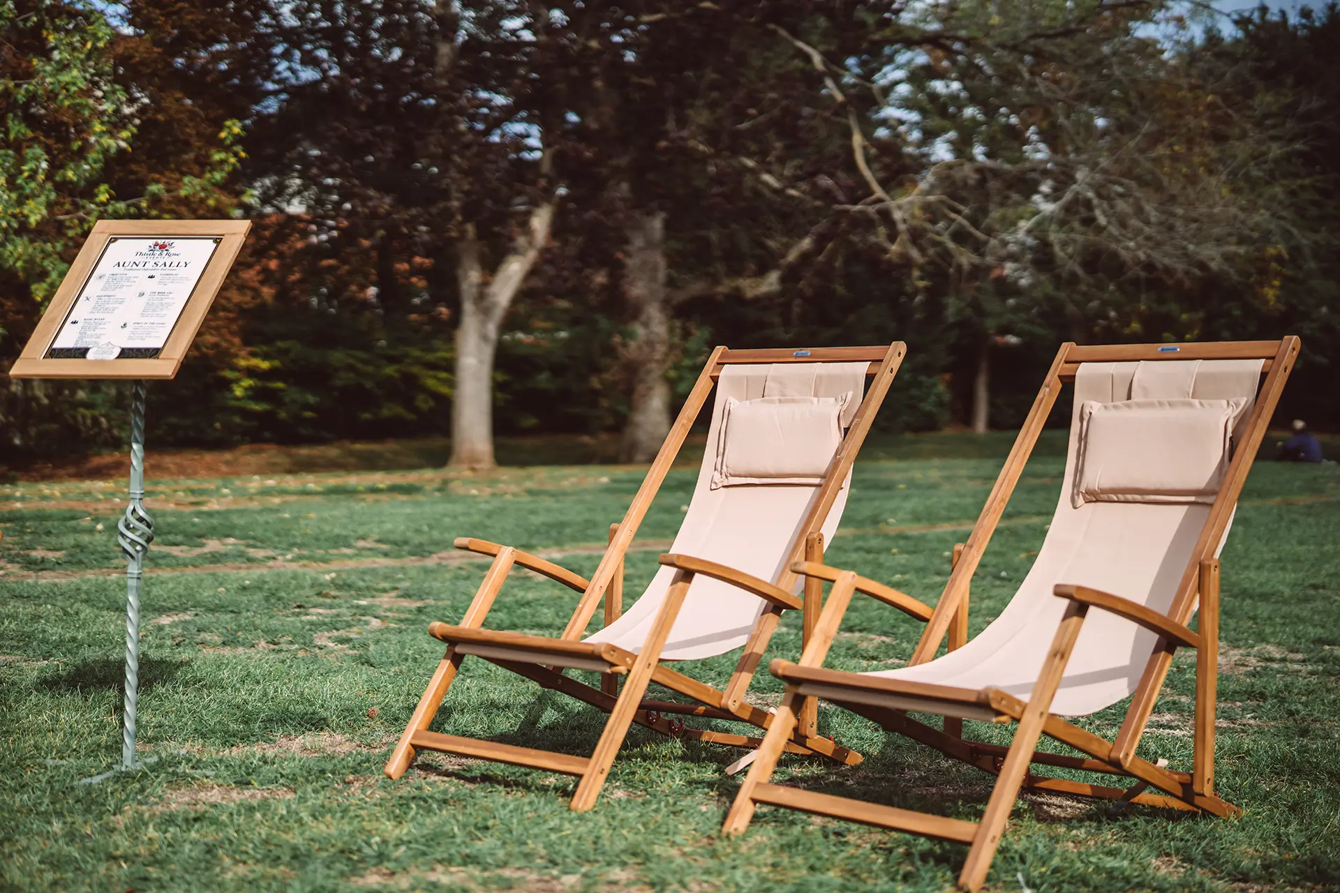 Two wooden easels set on grass under blue skies, by Thistle & Rose Events.